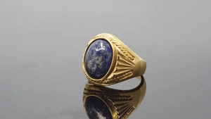Macro shot of gold signet ring with lapis lazuli stone and engraved side texture