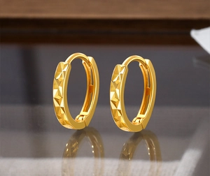 Detail view of gold S925 silver hoop earrings with geometric faceted diamond-cut surface