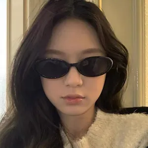 Fashionable black oval sunglasses with dark lenses for a retro minimalist street style look