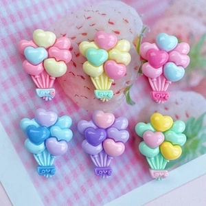 Détail macro de breloques en résine en forme de cœur avec gravure Love aux tons pastel