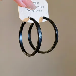 Detail showing a black geometric round hoop earring featuring an S925 silver needle