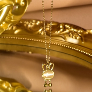 Macro shot of rabbit pendant necklace with cat-eye stone and golden tassel details