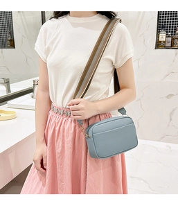 Light blue crossbody bag featuring a lychee texture and a wide striped shoulder strap