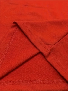 Détail de l'ourlet du t-shirt rouge montrant la couture à double aiguille et le tissu