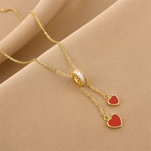 Elegant gold titanium necklace featuring a white zircon ring and twin red heart tassels