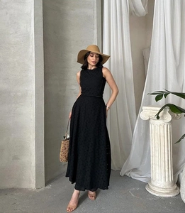 Détail de la robe longue noire sans manches avec une texture de broderie ajourée raffinée