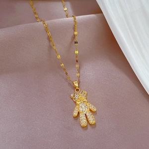 Elegante goldene Bärenkette mit glänzenden Strasssteinen auf weichem rosa Satinstoff