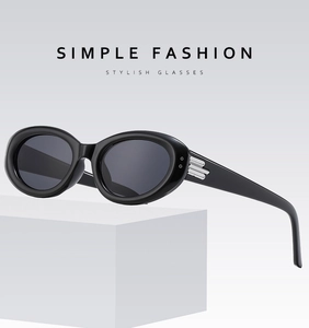 Détail de lunettes de soleil ovales noires avec charnières argentées sur support minimaliste
