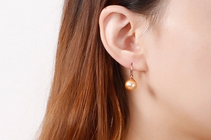 Gros plan d'une boucle d'oreille pendante en perle champagne sur le mannequin