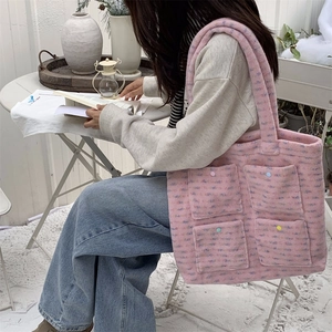 Detailed view of a pink plush tote bag with four colorful button pockets in winter setting
