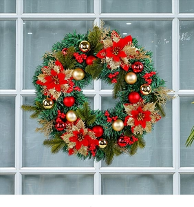 Detail of a Christmas wreath with poinsettias, berries, and ornaments on a white window
