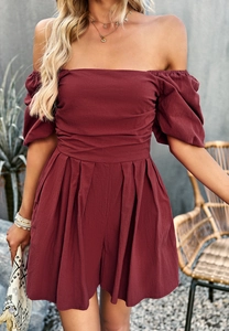 Detail of wine red off-shoulder romper with puff sleeves and waist pleats in outdoor setting
