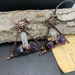 Detail of copper metal earrings with clear crystal pillars and raw purple stones
