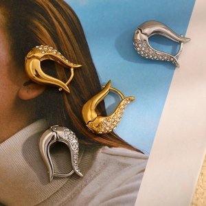 Close-up of U-shaped 18K gold plated earrings with paved crystals on a magazine background