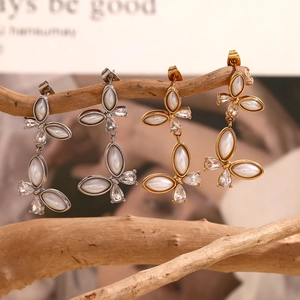 Detail of butterfly drop earrings in gold and silver finish with zircon and pearl accents