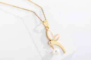 Macro detail of golden bunny pendant with opal ears, rhinestone neck, and pearl drop