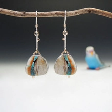 Ethnic style silver earrings with irregular turquoise stone pendants on wood branch
