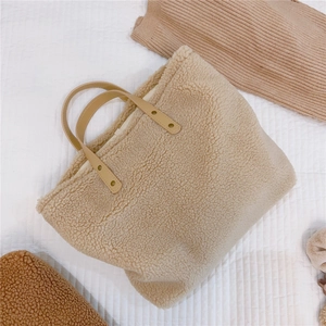 Detail of beige fleece tote bag with brown leather handles and metallic rivet accents