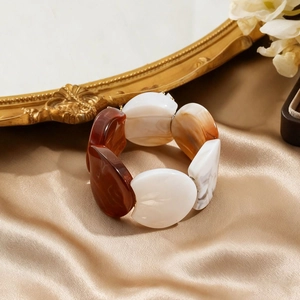 Detailed close-up of colorful resin acrylic bracelet on luxurious champagne satin cloth