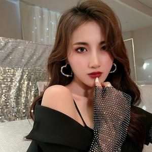 Close-up of heart-shaped rhinestone earrings and ring with black mesh gloves