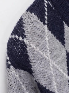 Detail shot of navy and grey argyle knit sweater with white dotted line textures