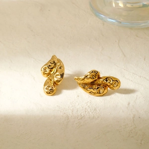 Elegant gold-tone irregular molten drop earrings on a minimalist stone texture background