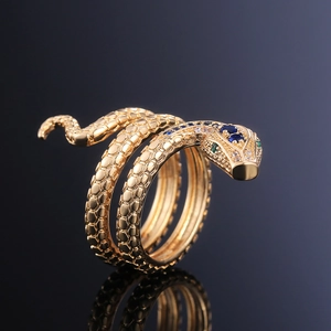 Foto macro de anillo de serpiente dorado con escamas de circonita y gema azul de pera