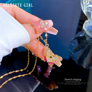 Close-up of gold butterfly pendant featuring pink zircons and micro-pave crystals