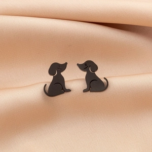 Macro view of matte black puppy stud earrings on elegant silk fabric background