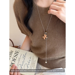 Detail of adjustable leather horse pendant necklace with wooden beads on sweater
