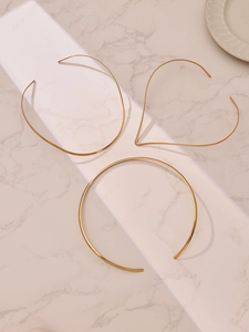 Détails de colliers minimalistes en acier inoxydable doré sur une surface en marbre