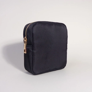 Close-up of black nylon cosmetic bag with golden zipper and smooth fabric texture