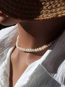 Close-up of elegant white freshwater pearl choker worn with a white textured shirt