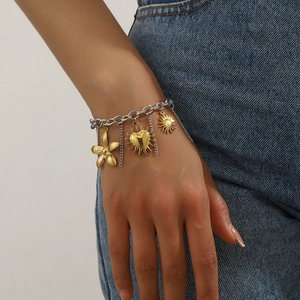 Detail of silver chain bracelet featuring gold flower and sun pendants on a model