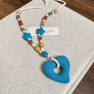 Detail of multi-color beaded necklace with a large blue heart lava stone pendant