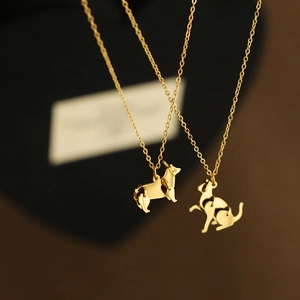 Detail of geometric origami dog and cat pendant necklaces in a polished gold finish