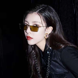 Close-up of retro brown rectangular sunglasses and gold disc earrings worn by a model