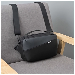 Detail of waterproof black nylon crossbody bag with Sport label on a gray sofa