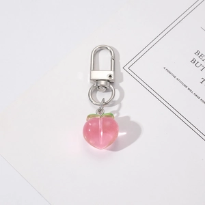 Pink peach resin charm with green leaves and silver lobster clasp on white background