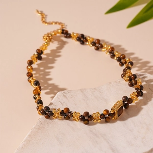 Detail of beaded necklace featuring brown tiger eye beads and gold floral metal accents