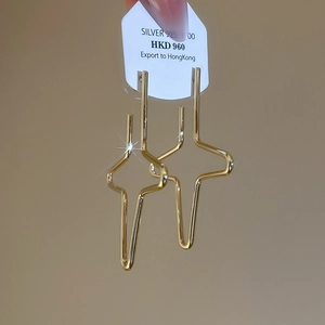 Detailed close-up of geometric star earrings in gold finish featuring 925 silver needles