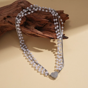 Détail du collier multicouche avec rangs de perles et pendentif cœur serti de diamants