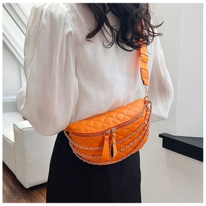 Detail of orange quilted waist bag featuring gold chain link straps and adjustable belt