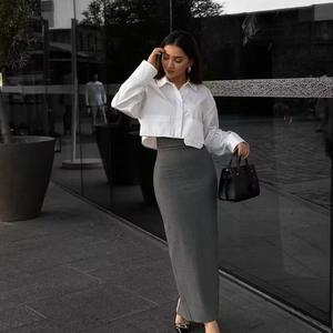 Detail of a white cropped long-sleeve shirt paired with a grey high-waist slim skirt