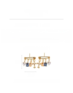 Detail view of gold safety pin earrings with zircon heart and cross charms