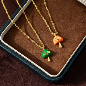 Macro shot of green and orange enamel mushroom necklaces with gemstones in a gift box