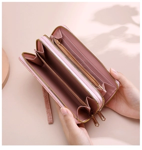 Detail of pink crocodile embossed long wallet featuring dual zippers and multiple card slots