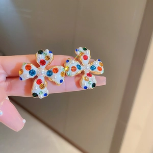 Detailed shot of cross-shaped earrings with colorful crystals and white pearls