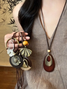 Close-up of wooden leaf pendant necklace with retro bronze charms and wax cord