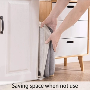 Space-saving foldable gray laundry basket being stored in a narrow gap between furniture